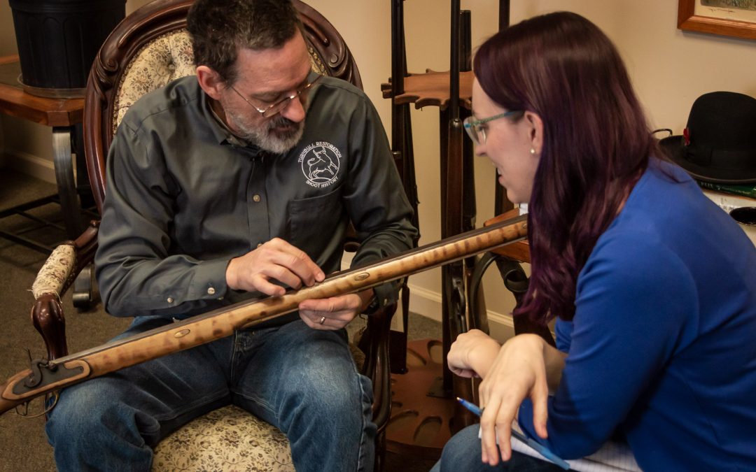 Photo of Doug Turnbull showing daughter Sara Turnbull a muzzleloader rifle that he built from a kit when he was 12 years old